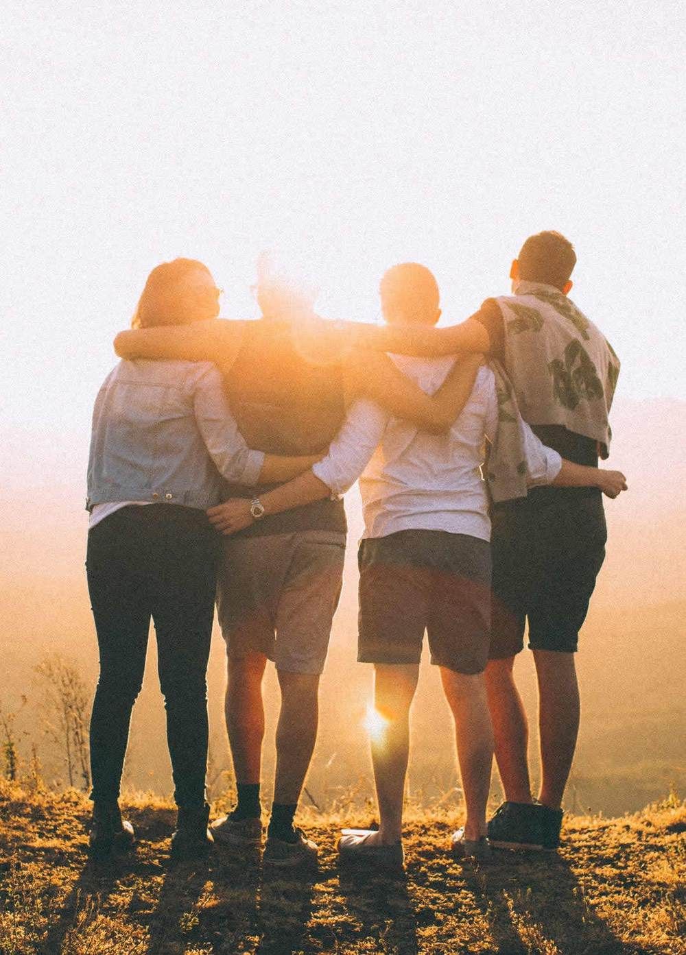 Behind look of friends hugging and facing the sunset
